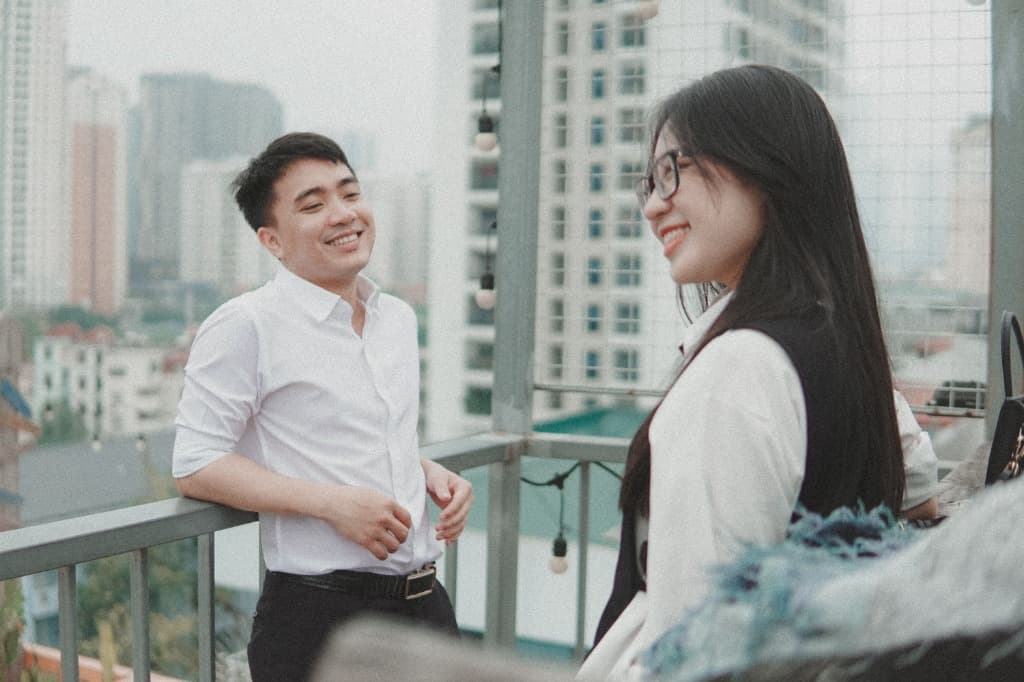 Two people talking and laughing on a rooftop above the city